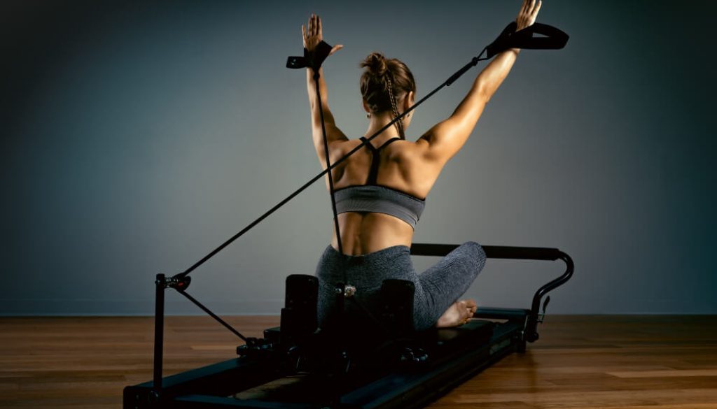 pilates-exercises-with-reformer-bed-beautiful-slim-fitness-trainer-fitness-concept